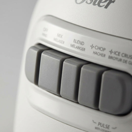 Macro close-up of gray control buttons on the white Oster 2169693 blender base.