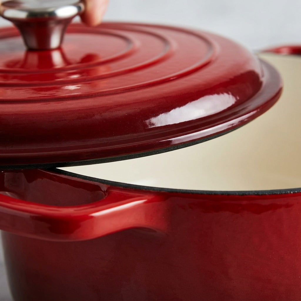 Extreme macro photo showing the detailed edge and concentric ring texture of the red enameled cast iron lid and the clean cream enamel interior of the dutch oven.