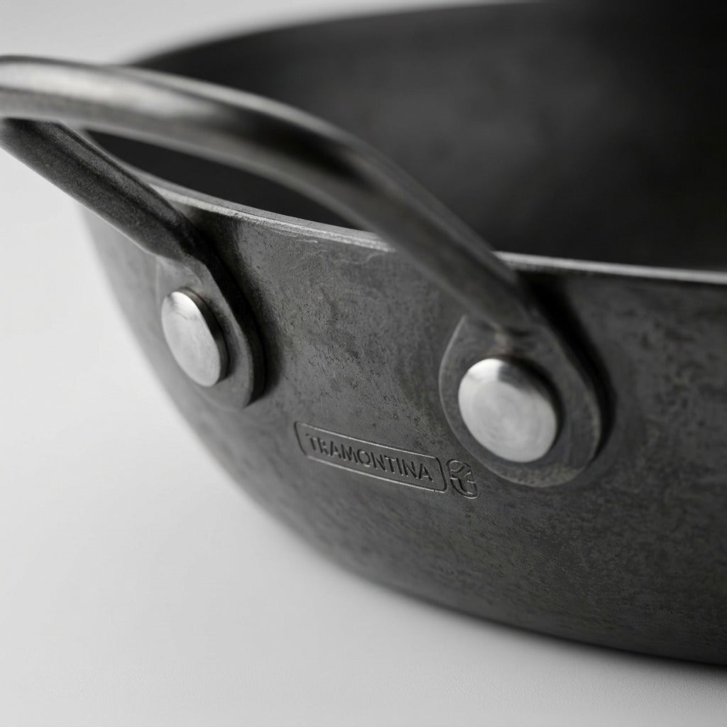 Macro photograph of the Tramontina carbon steel paella pan's handle rivet and texture.