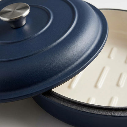 Macro detail of Tramontina enamel cast iron bread oven lid texture, steel knob, and cream interior.