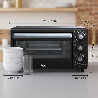 Black Oster Compact Air Fryer Oven with dimension lines shown next to a stack of bowls for scale.