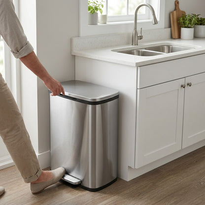 A person uses the foot pedal on a Tramontina 13 gallon stainless steel step can in a modern kitchen.