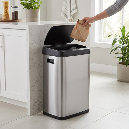 A person disposes of a paper bag into an open Tramontina 13 Gal stainless steel sensor trash can.